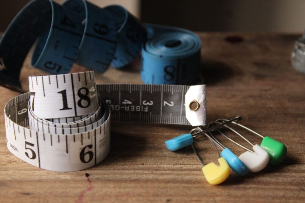 Tape measures and colorful sewing pins on a wooden surface.