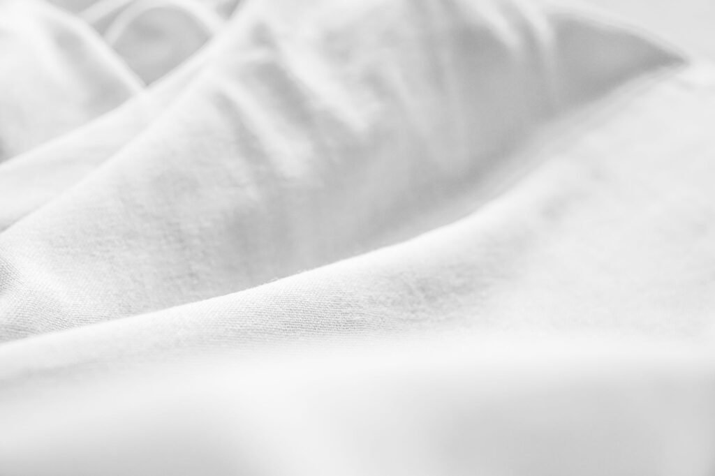 Detailed close-up of smooth white fabric showing subtle textures and wrinkles.
