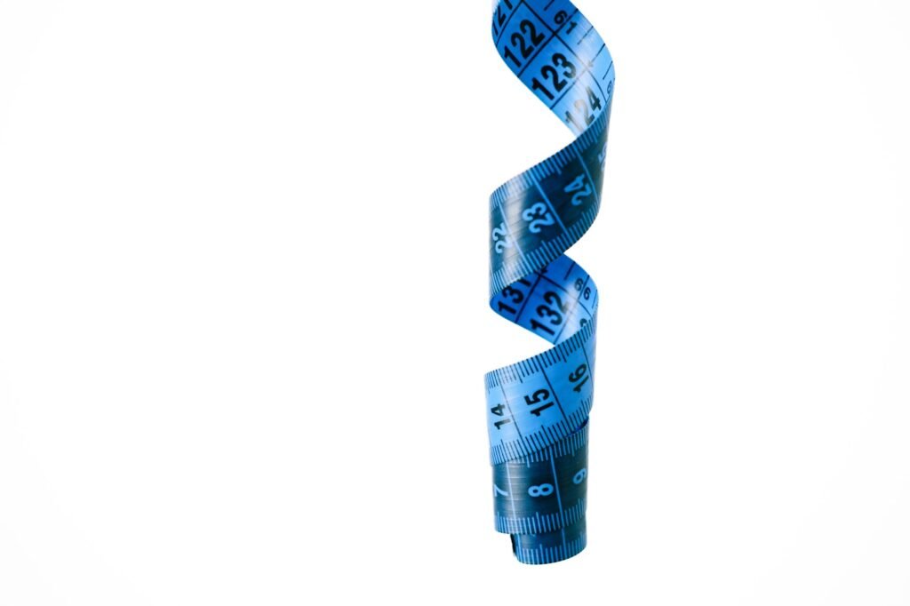 A close-up of a blue spiral measuring tape against a white background, symbolizing precision and measurement.