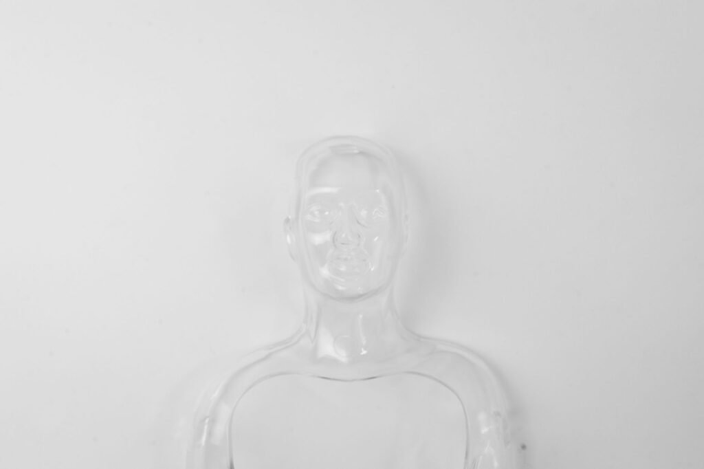 A clear glass figurine on a white backdrop showcasing minimalism and transparency.