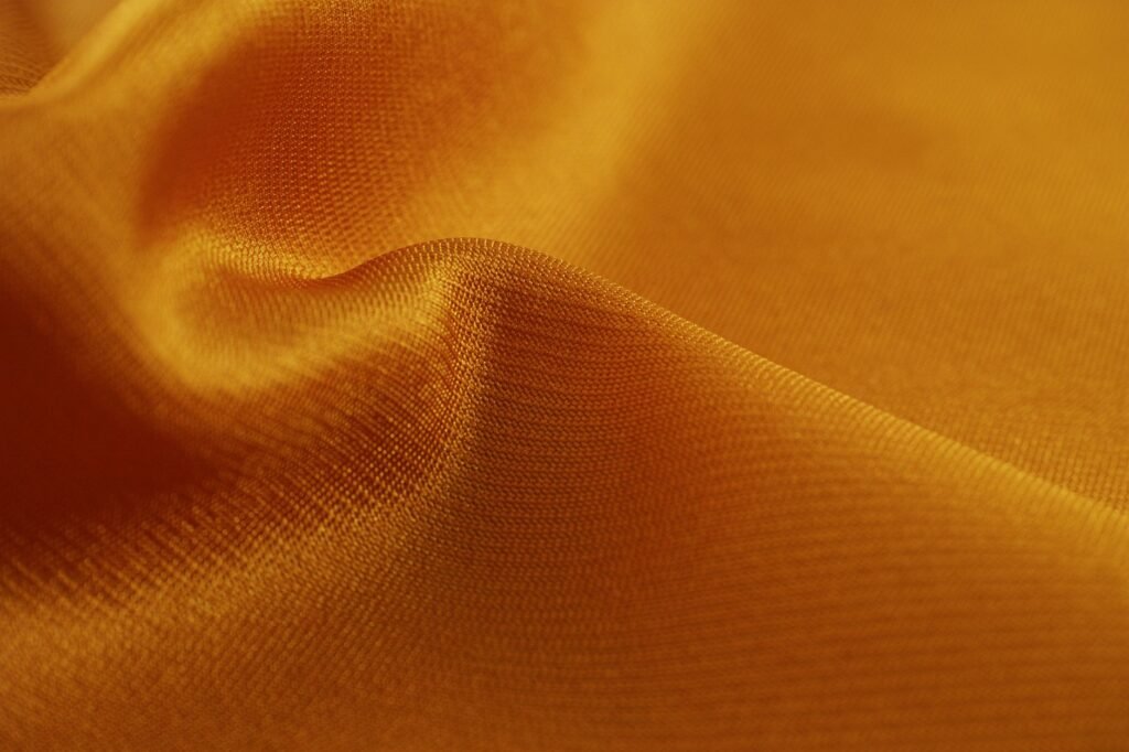 Close-up of a smooth, golden silk fabric showcasing its luxurious texture and shine.